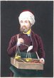 Moroccan Jew with beard and turban carrying a box containing spices and holding a pair of scales in